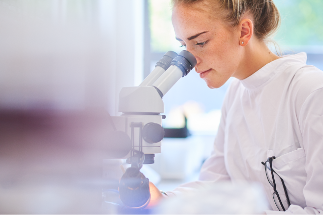 Female student scientist using a microscope