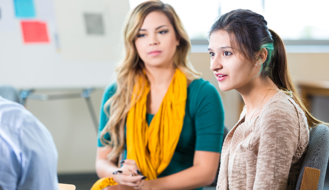 Two young women sitting in group during class