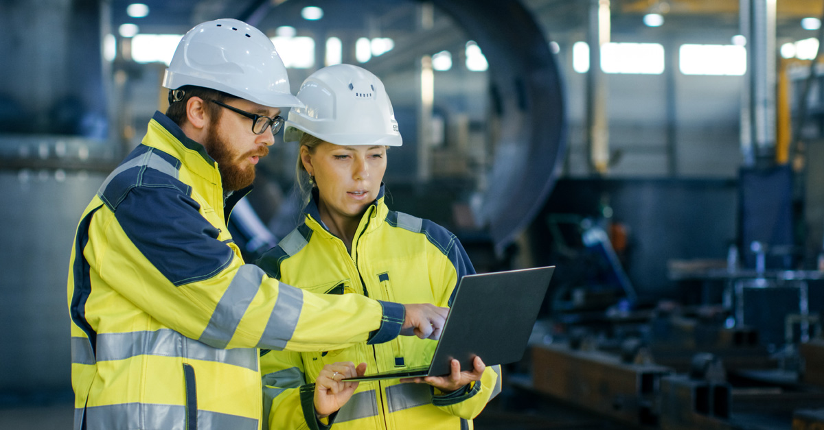 Man and woman in hard hats looking at a tablet