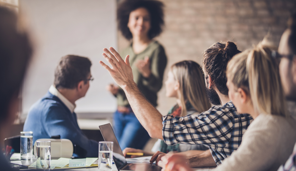 Woman calling on employee in group meeting